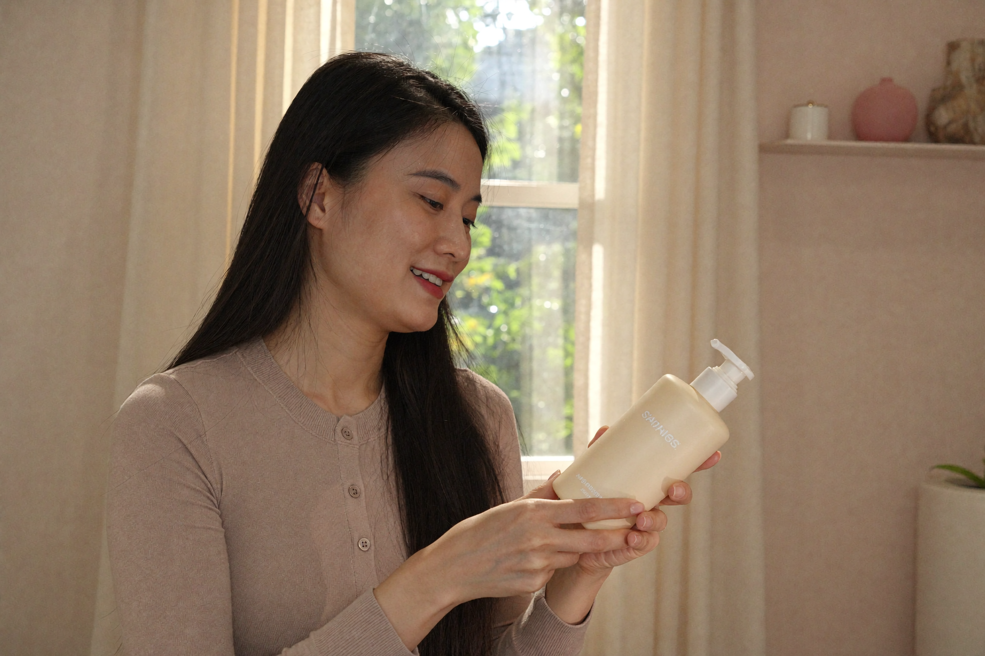 woman vietnamese self-care window cardigan shampoo bottle warm afternoon smile — Phụ nữ cạnh cửa sổ cầm chai dầu gội mỉm cười tự chăm sóc bản thân